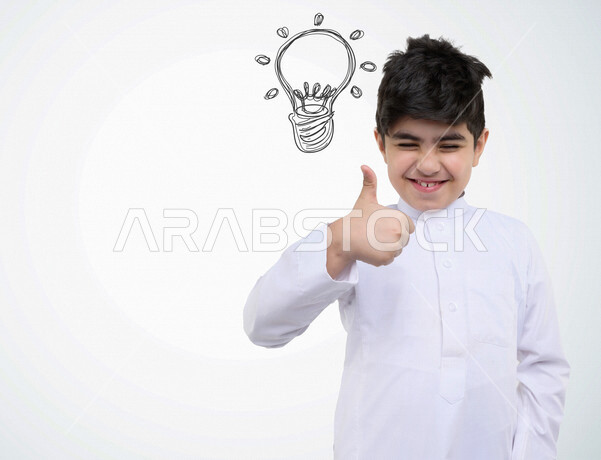 صورة مقربة لطفل خليجي سعودي مبتسم وسعيد ، ذو أفكار إبداعية عبقرية ، ايماءات الوجه واليدين تدل على الانجاز والنجاح، طفل مستقبلي مبتكر، خلفية بيضاء ومصباح