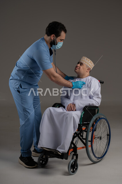 A doctor supervising the treatment of a person with special needs and determination, the concept of providing assistance, support and treatment, a portrait of an Arab Gulf Omani young man wearing a sleeve and a dishdasha sitting in a wheelchair, gray background