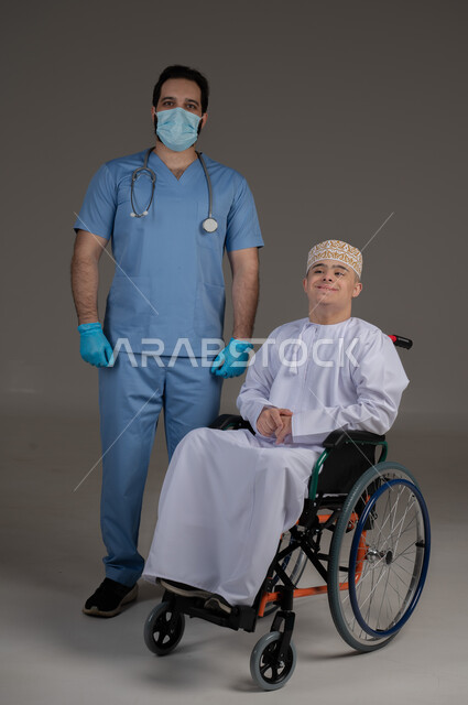 طبيب يشرف على علاج شخص من ذوي الإحتياجات الخاصة والهمم, مفهوم تقديم المساعدة والدعم والعلاج, بورتريه لشاب عربي خليجي عماني يرتدي الكمه والدشداشة يجلس على كرسي متحرك, خلفية رمادي