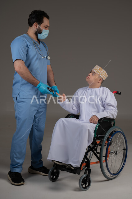 طبيب يشرف على علاج شخص من ذوي الإحتياجات الخاصة والهمم, مفهوم تقديم المساعدة والدعم والعلاج, بورتريه لشاب عربي خليجي عماني يرتدي الكمه والدشداشة يجلس على كرسي متحرك, خلفية رمادي