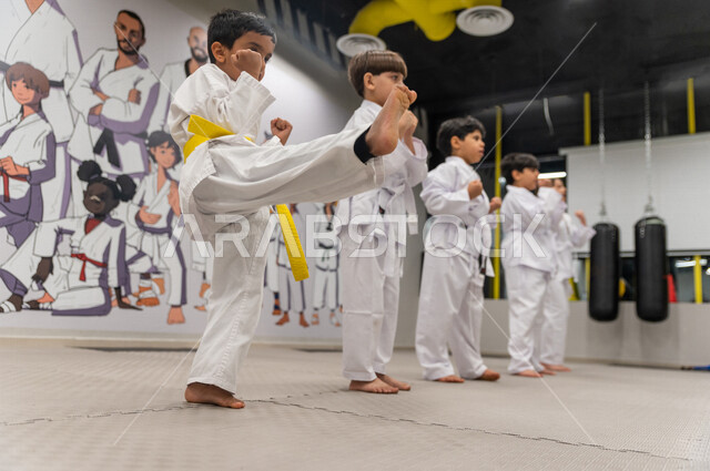 فتى عربي خليجي سعودي مع مجموعة من الفتيان يقوم  بالتدرب على حركات قتالية خاصة برياضة الكارتيه اليابانية ، التدرب على فنون الدفاع عن النفس ، رياضة دفاعية تتميز بالأخلاق العالية للاعبين