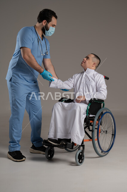 الاهتمام والاعتناء بمرضى ذوي الهمم، تقديم الخدمات الصحية، مفهوم الطب والرعاية الصحية، بورتريه لممرض يرتدي اليونيفورم يقدم العلاج لولد عربي خليجي عماني مقعد مصاب بمتلازمة داون يرتدي الدشداشة، صورة لكامل الجسم، خلفية رمادية