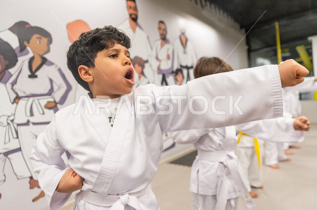 صورة مقربة لمجموعة من الفتيان العرب الخليجيين السعوديين يقومون بالتدرب على حركات قتالية خاصة برياضة الكارتيه اليابانية  من قبل المدرب الخاص ، التدرب على فنون الدفاع عن النفس ، رياضة دفاعية تتميز بالأخلاق العالية للاعبين