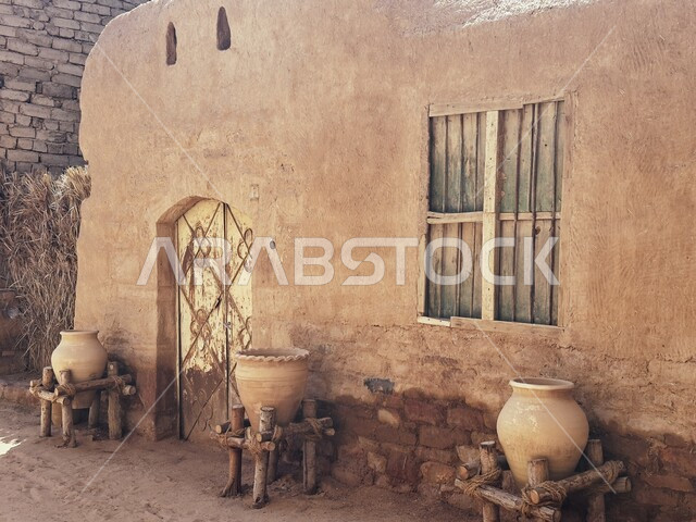 العراقة والحضارة العربية الأصلية، صورة مقربة لجرات مصنوعة من الفخار فوق الخشب أمام أبواب لمنازل في البلدة القديمة في العلا، المناطق السياحية الشعبية في المملكة العربية السعودية، البيوت والمنازل التراثية التاريخية من الطوب الطيني