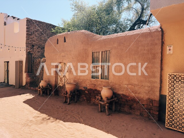 العراقة والحضارة العربية الأصلية، صورة مقربة لجرات مصنوعة من الفخار فوق الخشب أمام أبواب لمنازل في البلدة القديمة في العلا، المناطق السياحية الشعبية في المملكة العربية السعودية، البيوت والمنازل التراثية التاريخية من الطوب الطيني