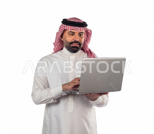 بورتريه لرجل سعودي خليجي بالزي السعودي التقليدي ، استخدام جهاز الحاسوب المحمول لإنجاز المهام والمشاريع ، خلفية بيضاء ، جلسة عمل، سيد أعمال، إنجاز المشاريع والمهام، العمل عن بعد ، مهن وأعمال تجارية ، التعليم الإلكتروني