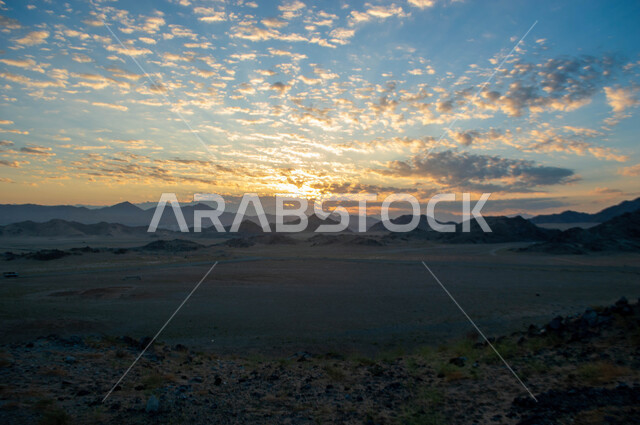 Topography, heights and mountain peaks in the wilderness, desert areas and natural environment, rock formations and formations in the desert of the Kingdom of Saudi Arabia, a sky full of clouds at sunset