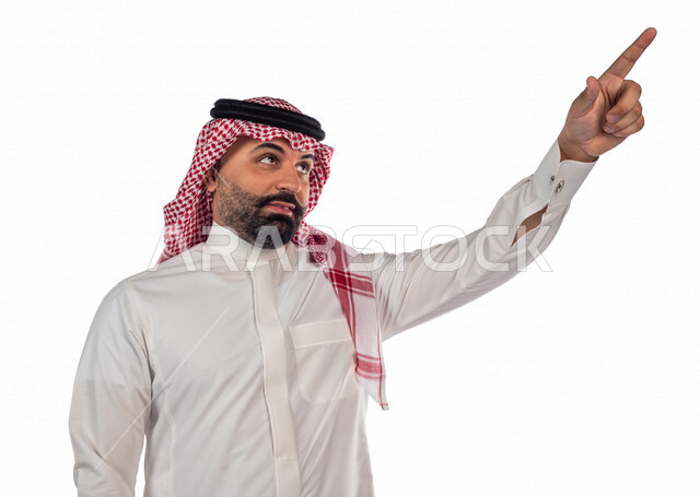 بورتريه لرجل سعودي خليجي يقوم بجلسة تصوير يشير بإصبعه لأعلى بإيماءات وجه ويدين مختلفة ، خلفية بيضاء لرجل سعودي مسلم يرتدي زي تقليدي سعودي مع شماغ وعقال