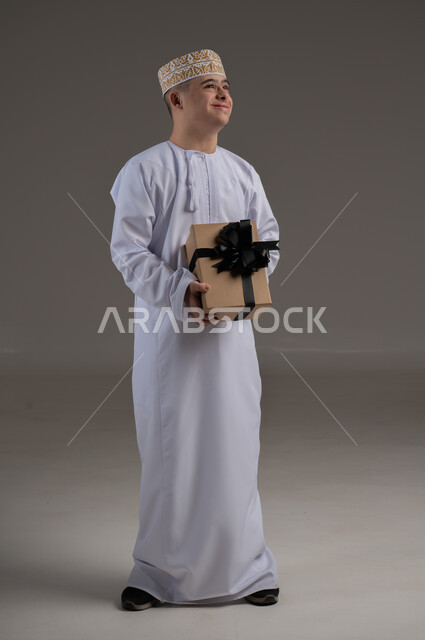 الاهتمام ودعم المجتمع العماني لذوي الاحتياجات الخاصة ، بورتريه لرجل عربي خليجي يرتدي الزي التقليدي يحمل بيده هدية, تقديم الحب و الرعاية،مفهوم طلب العون والمساعدة