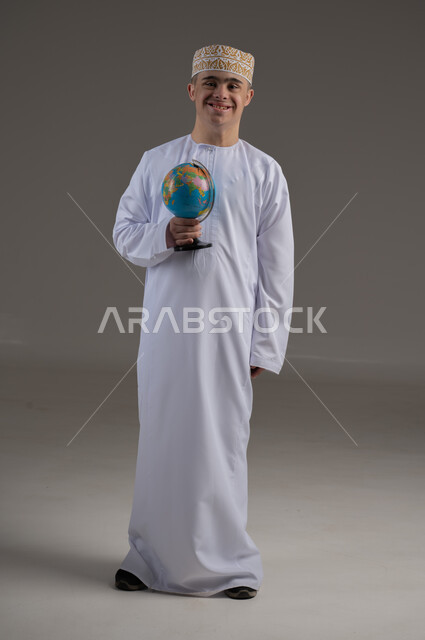 تقديم الحب و الرعاية، الاهتمام ودعم المجتمع العماني لذوي الاحتياجات الخاصة ، بورتريه لرجل عربي خليجي يرتدي الزي التقليدي يحمل بيده كرة العالم
