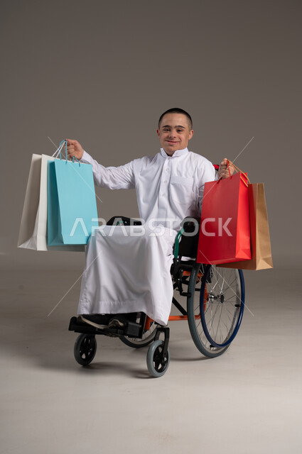 الاهتمام ودعم المجتمع السعودي لذوي الاحتياجات الخاصة ، بورتريه لرجل عربي خليجي يرتدي الزي التقليدي يحمل بيده اكياس تسوق, تقديم الحب و الرعاية،انشطة ترفيهية للمعاقين 