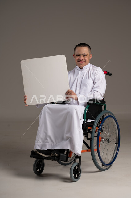 الاهتمام ودعم المجتمع السعودي لذوي الاحتياجات الخاصة ، بورتريه لرجل عربي خليجي يرتدي الزي التقليدي يحمل بيده لوحة بيضاء , تقديم الحب و الرعاية