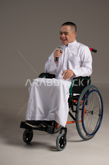 إيماءات وجه ويد تدل على السعادة، بورتريه لشاب عربي سعودي خليجي يرتدي الثوب التقليدي يحمل بيده مكريفون, التمكين الاجتماعي للمعاقين, اهتمام ودعم المجتمع السعودي لذوي الاحتياجات الخاصه, تقديم الحب و الرعاية