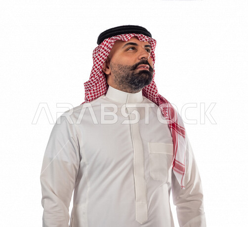 Portrait of a Saudi Gulf man doing a photo session looking up with different facial and hand gestures, white background of a Saudi Muslim man wearing a traditional Saudi costume with a shemagh and headband
