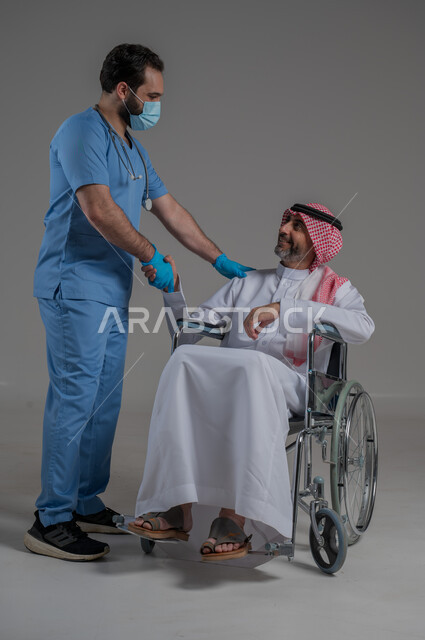 Gestures of joy and happiness, concept of healthcare and caring for patients and the disabled, lifestyle of people with disabilities, portrait of a nurse wearing a uniform and a mask taking care of a disabled Saudi Arabian Gulf man wearing a traditional thobe and shemagh sitting on a wheelchair, full body image, gray background