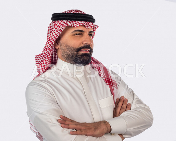 بورتريه بصورة مقربة لرجل سعودي خليجي يقوم بجلسة تصوير بإيدي متقاطعة بإيماءات وجه ويدين مختلفة ، منظر جانبي لرجل سعودي يرتدي زي تقليدي سعودي مع شماغ وعقال ، خلفية بيضاء