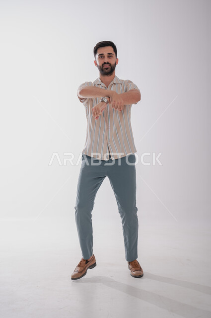 Looking at the camera with expressions of joy and pleasure, standing with crossed hands, portrait of a smiling Saudi Gulf Arab man, full length body, white background