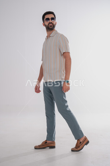 مفهوم الاناقة والشياكة، بورتريه لرجل عربي خليجي سعودي يقف بايماءت الثقة بالنفس الاهتمام بالمظهر الخارجي واللباقة، الجسم بالطول الكامل, خلفية بيضاء