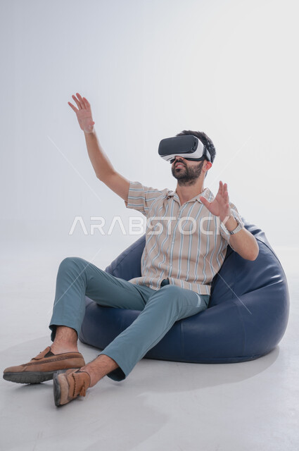 إيماءات الاندماج والتفاعل مع العالم الخيالي, بورتريه لرجل عربي خليجي سعودي يضع نظارة الفي آر ثلاثية الأبعاد، محاكاة الواقع الافتراضي باستخدام التقنيات الحديثة المتطورة، خلفية بيضاء