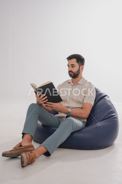 إنجاز الواجبات اليومية, قضاء الوقت بالمطالعة والتعلم والتثقف, بورتريه لرجل عربي خليجي سعودي يحمل بيده كتاب للقراءة, خلفية بيضاء