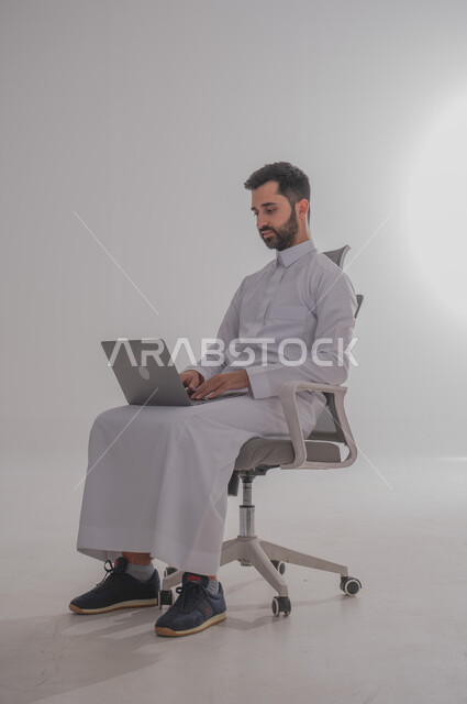 استخدام الأجهزة التقنية الحديثة, بورتريه لرجل عربي خليجي سعودي يرتدي  الثوب ويجلس على كرسي ويضع امامه حاسب محمول، الدردشة مع الأهل والأصدقاء, تصفح برامج التواصل الاجتماعي، تطبيقات الأجهزة الحاسوبية،  خلفية بيضاء