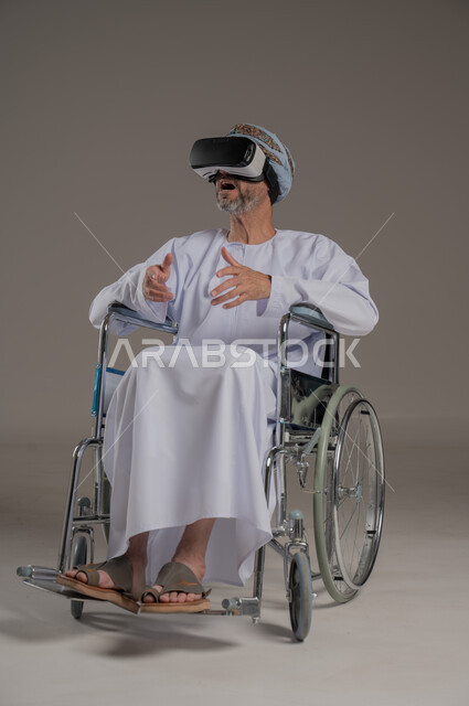 Simulating the imaginary world and interacting with the movie, improving the quality of life for people with motor disabilities, using wheelchairs to help with movement and mobility, portrait of an Arab Gulf Omani man wearing a turban and dishdasha watching movies through 3D virtual reality glasses, gray background