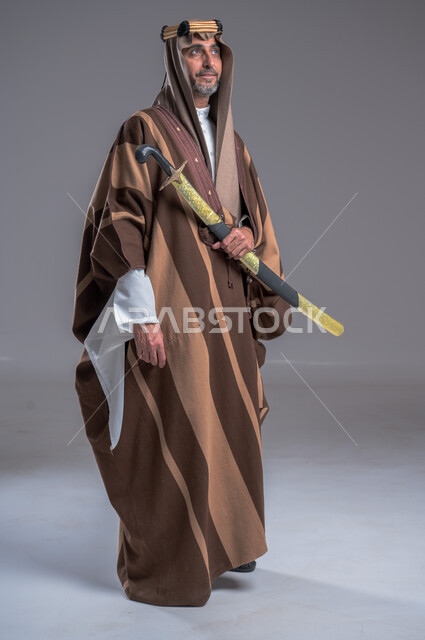ذكرى تأسيس الدولة الأولى 1727م، الوقوف باستقامة وشموخ، مفهوم الاصالة والعراقة عند العرب، بورتريه لرجل عربي خليجي سعودي يرتدي الدقلة والغترة والعقال الذهبي يحمل، يوم بدينا 22 فبراير, إحياء تراث المملكة, الاحتفالات بالمناسبات الوطنية, خلفية رمادية