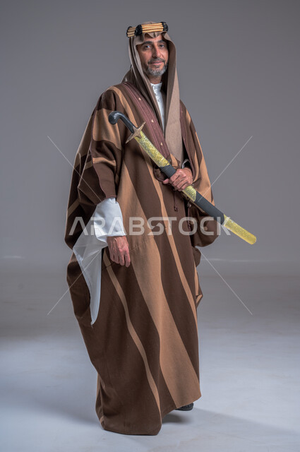 ذكرى تأسيس الدولة الأولى 1727م، الوقوف باستقامة وشموخ، مفهوم الاصالة والعراقة عند العرب، بورتريه لرجل عربي خليجي سعودي يرتدي الدقلة والغترة والعقال الذهبي يحمل، يوم بدينا 22 فبراير, إحياء تراث المملكة, الاحتفالات بالمناسبات الوطنية, خلفية رمادية