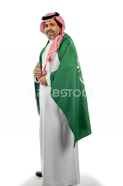 بورتريه رجل عربي خليجي سعودي يضع على ظهره  علم المملكة العربية السعودية ، ذكرى اليوم الوطني السعودي ،الاحتفال بالعيد الوطني السعودي