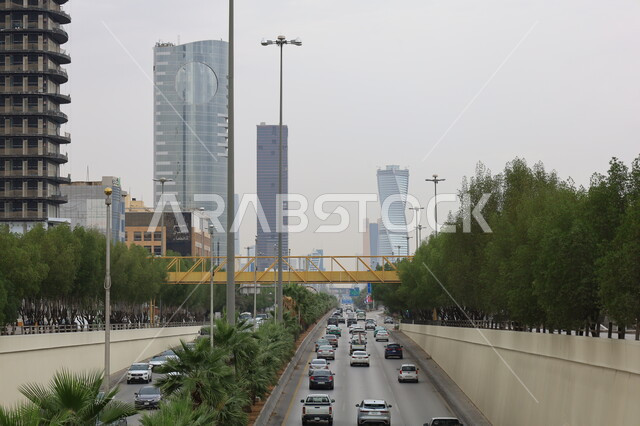 التطور والتقدم العمراني، الفن الهندسي المعماري للأبراج في مدينة الرياض، الاهتمام بزراعة الأشجار والمروج والنباتات الخضراء، حركة مرور السيارات في المملكة العربية السعودية، منظر السماء المليئة بالغيوم البيضاء نهارا، الطرق والشوارع المعبدة،  نمط الحياة في البلد