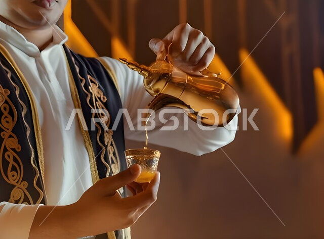 حسن الإستقبال وفق العادات والتقاليد الأصيلة, الاستمتاع بشرب البن العربي، التمسك بالقيم الكريمة المتوارثة من الأجداد، صورة مقربة لرجل عربي خليجي سعودي يقوم بصب القهوة في الفنجان، أساليب عريقة في كرم الضيافة