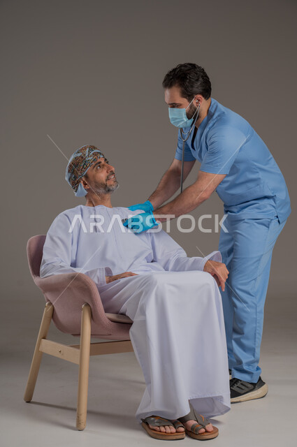 اجراءات الفحص الطبي العامة لكبار السن، بورتريه لممرض عربي خليجي  يلبس اليونيفورم والقفازات والكمامة الوقائية يقوم بفحص مريض عماني مسن يرتدي الدشداشة والعمامة يجلس على كرسي، استخدام الأدوات الطبية الحديثة، خلفية رمادية
