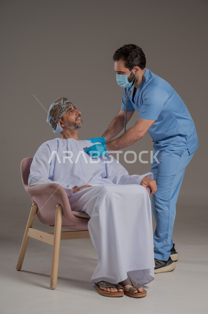 اجراءات الفحص الطبي العامة لكبار السن، بورتريه لممرض عربي خليجي  يلبس اليونيفورم والقفازات والكمامة الوقائية يقوم بفحص مريض عماني مسن يرتدي الدشداشة والعمامة يجلس على كرسي، استخدام الأدوات الطبية الحديثة، خلفية رمادية