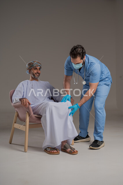 اجراءات الفحص الطبي العامة لكبار السن، بورتريه لممرض عربي خليجي  يلبس اليونيفورم والقفازات والكمامة الوقائية يقوم بفحص مريض عماني مسن يرتدي الدشداشة والعمامة يجلس على كرسي، استخدام الأدوات الطبية الحديثة، خلفية رمادية