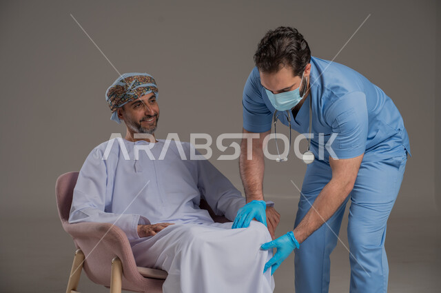 اجراءات الفحص الطبي العامة لكبار السن، بورتريه لممرض عربي خليجي  يلبس اليونيفورم والقفازات والكمامة الوقائية يقوم بفحص مريض عماني مسن يرتدي الدشداشة والعمامة يجلس على كرسي، استخدام الأدوات الطبية الحديثة، خلفية رمادية