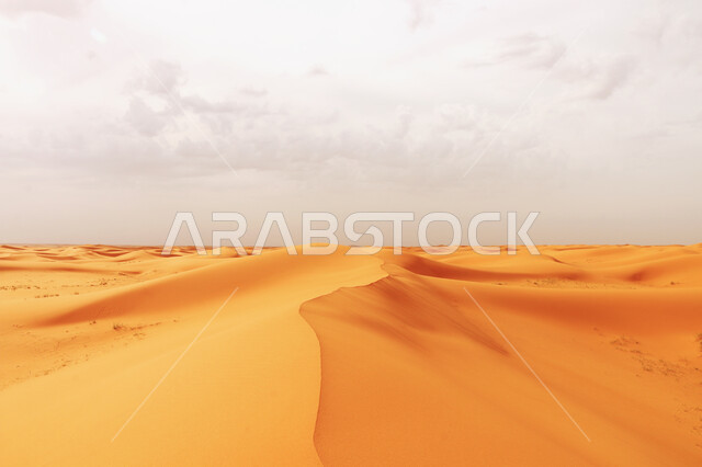 Thick white clouds in the sky of the Kingdom of Saudi Arabia, plateaus and hills of soft golden sand, desert areas and desert natural environment, sand dunes in the Great Arabian Desert