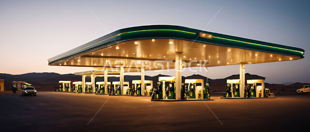 محطة محروقات مضيئة في أحد شوارع المملكة العربية السعودية، محطة بنزين متطورة في الطرقات، تزويد السيارات بالوقود اللازم لعملها وإكمال الطريق، وسائل النقل الحديثة والسريعة، خلفية السماء وقت غروب الشمس