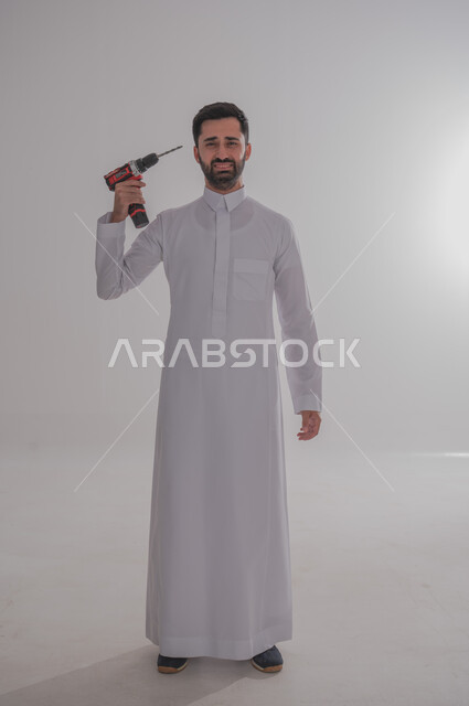 Skill and mastery of work, using maintenance tools and equipment to make repairs, portrait of a Saudi Arabian Gulf man wearing traditional thobe looking at the camera with crying gestures holding a piercing spear in his hand and pointing it towards his head, full length body, white background