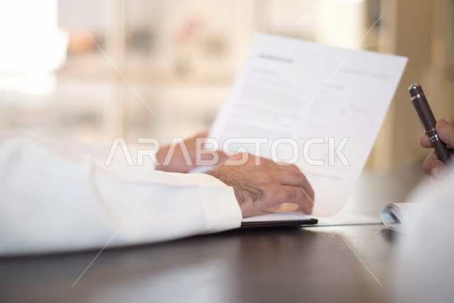 صورة مقربة لرجل اعمال عربي خليجي سعودي يمسك بيده قلم، توقيع عقد عمل بشركة سعودية خليجية، شركة سعودية، عقد عمل جديد، عقد شراكة، بيئة عمل