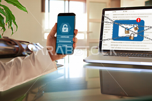 صورة مقربة ليد رجل عربي سعودي خليجي يحمل بيده هاتفه الذكي يقوم بالقفل والحماية بإستخدام تطبيق ذكي للتحكم من خلال هاتف محمول، الحماية على الهاتف المحمول وجهاز الحاسوب مع رموز القفل، الحماية والأمان، قفل جهاز اللابتوب بإستخدام تطبيق الهاتف الذكي