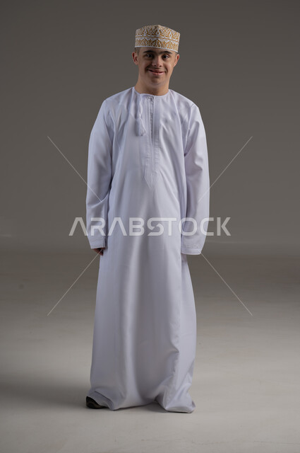 الوقوف باستعداد واستقامة، الاهتمام بالمظهر الخارجي والاناقة، بورتريه لرجل عربي خليجي عماني يرتدي الدشاشة والكمة يقف باستقامة وينظر الى الكاميرا بتعابير الجدية والثقة بالنفس، صورة الجسم بالطول الكامل، خلفية رمادية