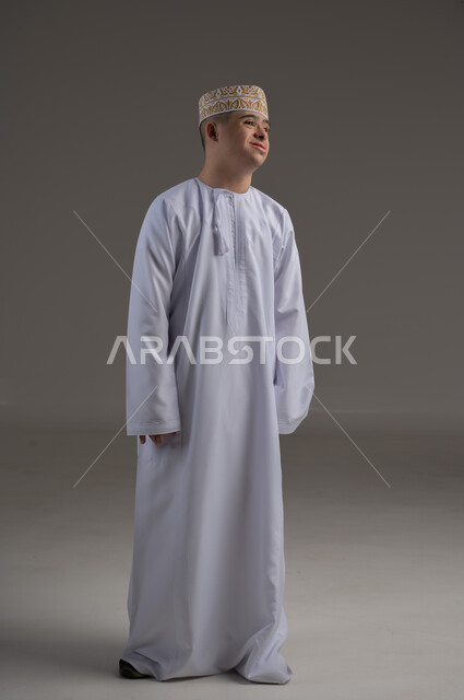 الوقوف باستعداد واستقامة، الاهتمام بالمظهر الخارجي والاناقة، بورتريه لرجل عربي خليجي عماني يرتدي الدشاشة والكمة يقف باستقامة وينظر الى الكاميرا بتعابير الجدية والثقة بالنفس، صورة الجسم بالطول الكامل، خلفية رمادية