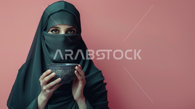 الاستمتاع بالمشروبات الساخنة، الاهتمام بالمظهر الخارجي والأناقة، ملابس محجبات عصرية راقية، مفهوم الأنوثة والنعومة، بورتريه لامرأة عربية خليجية سعودية محجبة تنظر  بايماءات الثقة بالنفس تحمل بيدها كوب من الشاي