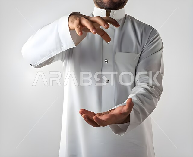 تحديد الحجم والكتله، استعمال اليدين لتحجيم شيء ما، بورتريه لرجل عربي خليجي سعودي يرتدي الزي التقليدي يقف باستقامة ويقوم برفع يديه بايماءات حمل شيء ما، مفهوم تقديم وعرض عنصر معين، خلفية بيضاء