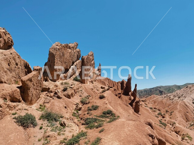 Rocky peaks and heights in the middle of the sandy environment, landscapes in the desert areas of the Kingdom of Saudi Arabia, formations and formations of stone rocks in the desert, growth of wild plants in the desert, mountainous nature terrain