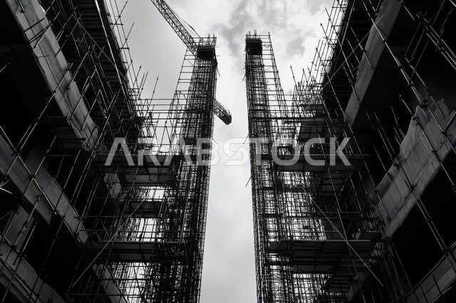 مبنى قيد الانشاء في المملكة العربية السعودية, أعمال البناء وصب الخرسانات ووضع الأساسات, تنفيذ مخطط الإعمار وتشكيل الهيكل المعدني، صورة بالأبيض والأسود لبرج تحت التشييد باستخدام الآليات الحديثة، مفهوم الهندسة الانشائية والمعمارية