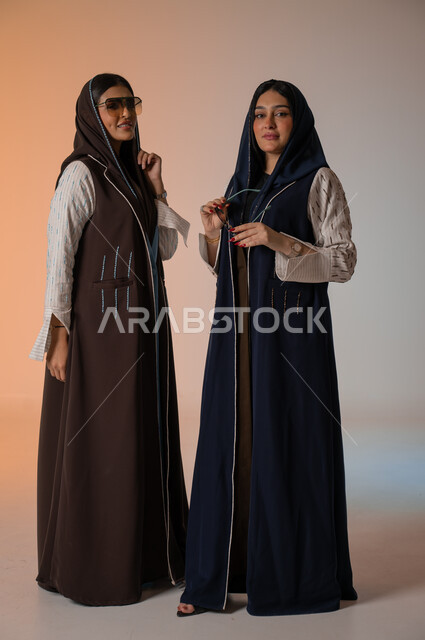ارتداء العباءة الخليجية والنظارات الشمسية، ايماءات الثقة والوقوف أمام الكاميرا، الاحتراف في عرض آخر صيحات الموضة والجمال، بورتريه لعارضتان عربيتان سعوديتان خليجيتان، صورة الجسم بالطول الكامل، منتجات نسائيه سعوديه، شراء الأزياء والاكسسوارات, خلفية ملونة 