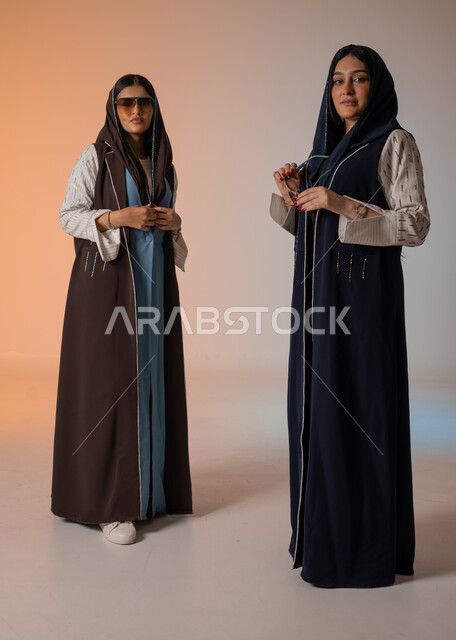 ارتداء العباءة الخليجية والنظارات الشمسية، ايماءات الثقة والوقوف أمام الكاميرا، الاحتراف في عرض آخر صيحات الموضة والجمال، بورتريه لعارضتان عربيتان سعوديتان خليجيتان، صورة الجسم بالطول الكامل، منتجات نسائيه سعوديه، شراء الأزياء والاكسسوارات, خلفية ملونة 
