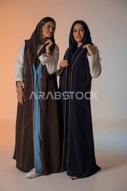  ايماءات الثقة والوقوف أمام الكاميرا، ارتداء العباءة الخليجية والنظارات الشمسية، الاحتراف في عرض آخر صيحات الموضة والجمال، بورتريه لعارضتان عربيتان سعوديتان خليجيتان، صورة الجسم بالطول الكامل، منتجات نسائيه سعوديه، شراء الأزياء والاكسسوارات, خلفية ملونة 
