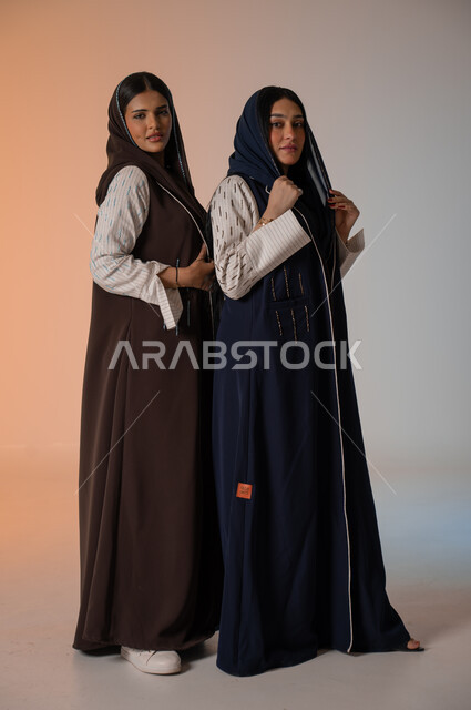  ايماءات الثقة والوقوف أمام الكاميرا، ارتداء العباءة الخليجية والنظارات الشمسية، الاحتراف في عرض آخر صيحات الموضة والجمال، بورتريه لعارضتان عربيتان سعوديتان خليجيتان، صورة الجسم بالطول الكامل، منتجات نسائيه سعوديه، شراء الأزياء والاكسسوارات, خلفية ملونة 